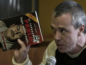 In this June 27, 2006, file photo, Jhon Jairo Velasquez, a former hit man for Pablo Escobar, gives his testimony while holding a book titled "The True Pablo, Blood, Treason, and Death," during the trial against Alberto Santofimio Botero in Bogota, Colombia. Colombian authorities are seeking to re-arrest the former hit man for Escobar for violating his parole after he was caught partying with a major drug trafficker. The chief prosecutor’s office said Saturday, Dec. 9, 2017, that Velasquez’s presence at a raucous birthday party for the Juan Carlos Mesa constituted a “very serious” offense. (AP Photo/William Fernando Martinez, File)