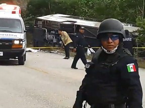 Video grab of Mexican police officers standing guard in the area where a bus driving tourists to Chacchoben archaeological zone overturned in the road between El Cafetal and Mahahual, in Quintana Roo state, Mexico on December 19, 2017.  (EMANUEL JESUS ORTEGA CANCHE/AFP/Getty Images)