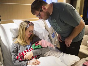In this Dec. 25, 2017 photo, Hannah Lindeman holds her newborn daughter, Poppy, in her hospital room at United Hospital in St. Paul, Minn.  Sitting behind Hannah is her husband, Taylor.