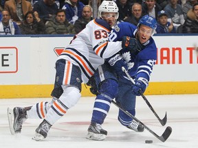Matt Benning of the Edmonton Oilers battles against Dominic Moore of the Toronto Maple Leafs during an NHL game on Dec. 10, 2017