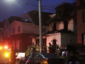 Police and firefighters converge on the scene of a fatal house fire, right, Monday, Dec. 18, 2017, in the Sheepshead Bay neighborhood in the Brooklyn borough of New York.