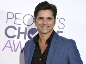 FILE - In this Jan. 18, 2017 file photo, John Stamos arrives at the People's Choice Awards at the Microsoft Theater in Los Angeles. Stamos announced his engagement to actress Caitlin McHugh on social media Oct. 22, 2017.