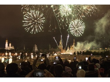 People take pictures as fireworks explode over the Kremlin, during New Year celebrations in Moscow, Russia, Monday, Jan. 1, 2018. New Year is Russia's major gift-giving holiday.