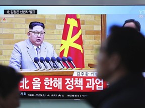 Visitors walk by a TV screen showing a TV news program reporting about North Korean leader Kim Jong Un's New Year's speech, at the Seoul Railway Station in Seoul, South Korea, Monday, Jan. 1, 2018. The letters read on top left, "Kim Jong Un delivers New Year's speech." Kim said the United States should be aware that his country's nuclear forces are now a reality, not a threat.