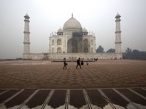 FILE - In this Dec. 5, 2017, file photo, tourists walk around Taj Mahal as workers clean the monument in Agra, India. The travel guidebook publisher Fodor's has published a list of where not to go in 2018 that includes the Taj Mahal. (AP Photo/Manish Swarup, File)