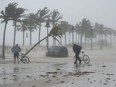 Two guys walks their bicycle along a flooded street on the waterfront of Fort Lauderdale as Hurricane Irma blows in Sunday, September 10, 2017.