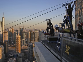Two people prepare to ride the world's longest urban zip line, with a speed of up to 80 km/h, in the Marina district of Dubai, United Arab Emirates, Tuesday, Dec. 5, 2017.