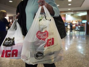 In this file photo, a woman leaves a grocery store in Montreal carrying plastic bags on Friday, May 15, 2015.