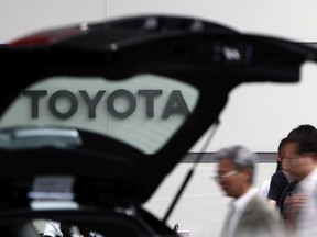 In this Aug. 2, 2011 file photo, people walk by a car on display at Toyota's Tokyo, Japan, headquarters.  (AP Photo/Shizuo Kambayashi, File)