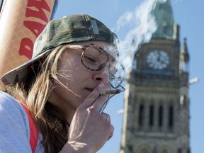 A woman smokes a joint during the annual 420 marijuana rally on Parliament hill on Wednesday, April 20, 2016 in Ottawa.