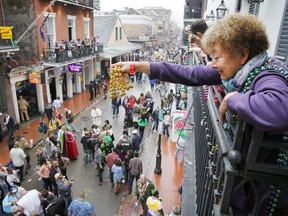 A Mardi Gras reveler dangles a pair of beads off of a balcony on Bourbon Street in New Orleans on Mardi Gras Day.