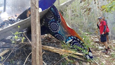 This photo released by Costa Rica's Public Safety Ministry shows people standing at the site of a plane crash near in Punta Islita, Guanacaste, Costa Rica, Sunday, Dec. 31, 2017. (Costa Rica's Public Safety Ministry via AP)