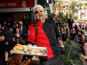 Chef and television personality Guy Fieri laughs as he serves hamburgers to guests during a welcome event for Guy Fieri's Vegas Kitchen & Bar at The Quad Resort & Casino on April 4, 2014 in Las Vegas, Nevada.