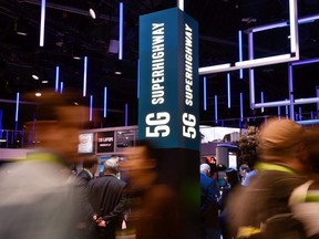 Attendeess pass by signage for 5G technology at the Intel booth during CES 2018 at the Las Vegas Convention Center on January 9, 2018 in Las Vegas, Nevada.