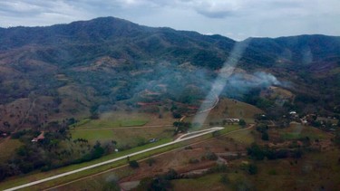 This photo released by Costa Rica's Public Safety Ministry shows smoke rising from the site of a plane crash near an air strip in Punta Islita, Guanacaste, Costa Rica, Sunday, Dec. 31, 2017. (Costa Rica's Public Safety Ministry via AP)