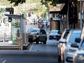 A white SUV (C) sits in the middle of the road as police and emergency personnel work at the scene of where a car ran over pedestrians in Flinders Street in Melbourne on December 21, 2017. The car ploughed into a crowd in Australia's second-largest city on December 21 in what police said was a "deliberate act" that left more than a dozen people injured, some of them seriously.