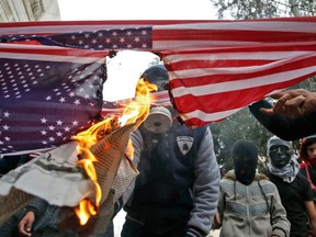 Palestinian protestors burn a US flag during clashes with Israeli security forces near a checkpoint in the city centre of the West Bank town of Hebron on December 22, 2017.