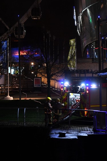 Firefighters take water from a dock as a blaze engulfs vehicles parked at a multi-storey car park (L) near the Echo Arena, at the waterfront in Liverpool on Dec. 31, 2017. (PAUL ELLIS/AFP/Getty Images)