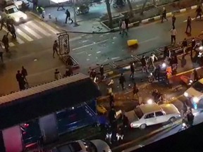An image grab taken from a handout video released by Iran's Mehr News agency reportedly shows a group of men pushing traffic barriers in a street in Tehran on December 30, 2017.