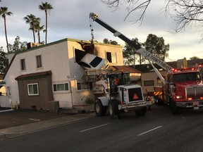 In this Sunday, Jan. 14, 2018, photo provided by Orange County Fire Authorit, a vehicle that crashed into a building hangs from a second story window in Santa Ana, Calif. (Capt. Stephen Horner /Orange County Fire Authority via AP)