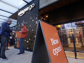 A customer is handed a complimentary shopping bag as he heads into an Amazon Go store, Monday, Jan. 22, 2018, in Seattle.