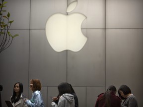 In this Oct. 20, 2017, file photo, people stand in line near an Apple Store at an outdoor shopping mall in Beijing, China. On Wednesday, Jan. 17, 2018, Apple announced it is planning to build another corporate campus and hire 20,000 workers during the next five years as part of a $350 billion commitment to the U.S. economy.