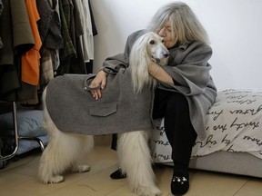In this image taken on Thursday, Jan. 11, 2018, designer Giovanna Temellini kisses her dog Ulisse, an Afghan greyhound, wearing a winter coat created by Ms. Temellini, at the Temellini manufacture headquarters, in Milan, Italy. Milan has long been known for its pret-a-porter. Now the pooches want in with a new line of haute couture for canines: Temellini Dog a Porter.