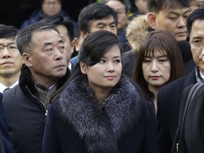 North Korean Hyon Song Wol, center, head of a North Korean art troupe, watches while South Korean protesters stage a rally against her visit in front of Seoul Railway Station in Seoul, South Korea, Monday, Jan. 22, 2018. Dozens of conservative activists attempted to burn a large photo of North Korean leader Kim Jong Un as the head of the North's extremely popular girl band passed by them at a Seoul railway station Monday following a visit to potential venues for performances during next month's Winter Olympics.