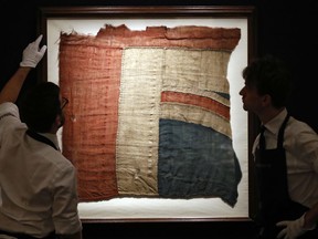 Sotheby's employees look at a frame with a fragment of a Union Jack in London, Thursday, Jan. 11, 2018.