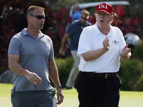 In this Friday, Dec. 29, 2017 file photo, U.S. President Donald Trump walks with Gene Gibson, commanding officer at Coast Guard Station Lake Worth Inlet, as he arrives to meet with members of the U.S. Coast Guard, who he invited to play golf, at Trump International Golf Club, in West Palm Beach, Fla. (AP Photo/Evan Vucci, File)