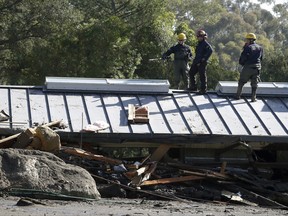 Emergency crew members search an area near houses damaged by storms in Montecito, Calif., Friday, Jan. 12, 2018.