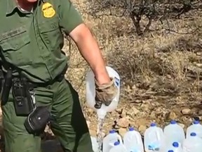 In this screenshot, a U.S. Border Patrol agent allegedly pours out water left for illegal immigrants.