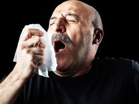 Middle-aged man with flu sneezing into a handkerchief