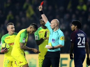 Referee Tony Chapron gives a red card to Nantes defender Diego Carlos, left, after Carlos inadvertently clipped the referee's heels during the French League One match between Nantes and Paris Saint Germain, in Nantes, Jan. 14, 2018.