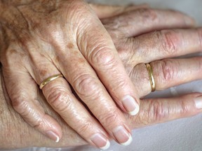 In this stock photo, a married senior couple embrace hands.