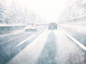 This stock photo shows cars driving on a highway during a snow storm.