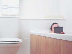 This stock photo shows a woman in a bathtub reading on a tablet.