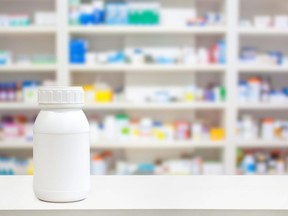 In this stock photo, a blank white medicine bottle sits on the counter of a pharmacy.