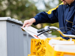 In this stock photo, a postman delivers boxes of mail.