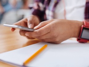 This stock photo shows a student using their smartphone in a classroom.