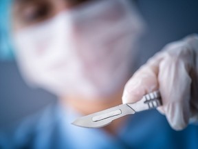 In this stock photo, a surgeon holds a scalpel during a procedure.