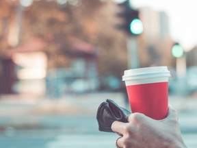 In this stock photo, a woman holds a hot beverage across from a traffic light.