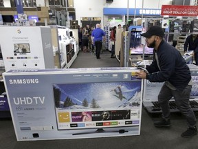 In this Thursday, Nov. 23, 2017, file photo, Jesus Reyes pushes a television down an aisle as he shops at a Black Friday sale at a Best Buy store in Overland Park, Kan.