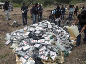 In this July 10, 2012 file photo, masked police pour gas on seized cocaine before burning it at a dump on the outskirts of Tegucigalpa, Honduras.