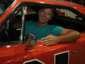 Actor John Schneider, who portrayed Bo Duke on the television series Dukes of Hazzard, leans out of the General Lee during the annual Spring Sportsman Show and Northern Ontario Fan Expo at the McIntyre Arena in Timmins on April 21, 2012.