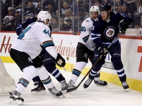 San Jose Sharks' Justin Braun and Winnipeg Jets' Patrik Laine battle for the puck on Jan. 7, 2018