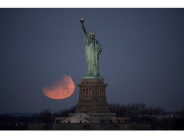 The Statue of Liberty is backdropped by a supermoon, Wednesday, Jan. 31, 2018, seen from the Brooklyn borough of New York. (AP Photo/Julio Cortez)