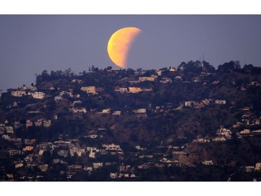 A super blue blood moon is seen setting behind the Hollywood hills in Los Angeles on Wednesday Jan. 31, 2018. The moon is putting on a rare cosmic show. It's the first time in 35 years a blue moon has synced up with a supermoon and a total lunar eclipse. NASA is calling it a lunar trifecta: the first super blue blood moon since 1982. That combination won't happen again until 2037.