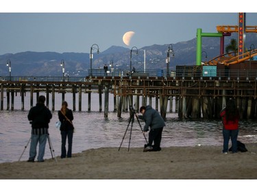 People take photos a rare occurrence called a 'Super Blue Blood Moon' at Santa Monica Beach in Santa Monica, Calif., Wednesday, Jan. 31, 2018.   It's the first time in 35 years a blue moon has synced up with a supermoon and a total lunar eclipse, or blood moon because of its red hue. Hawaii and Alaska had the best seats, along with the Canadian Yukon, Australia and Asia. The western U.S. also had good viewing, along with Russia.