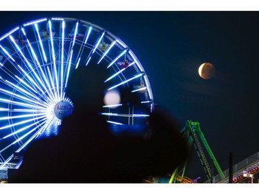 A man is silhouetted takes photo of a rare occurrence called a Super Blue Blood Moon at Santa Monica Beach in Santa Monica, Calif., Wednesday, Jan. 31, 2018. (AP Photo/Ringo H.W. Chiu)